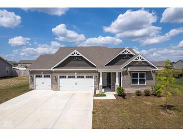 Beautiful brick home featuring a three-car garage, landscaped yard, and a charming covered porch at 7834 Fairwood Blvd, Plainfield, IN 46168