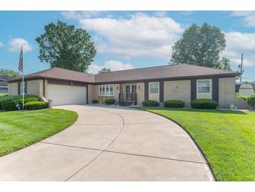 Charming brick ranch home with lush lawn, curved driveway, and attached two car garage at 8209 Burn Ct, Indianapolis, IN 46217
