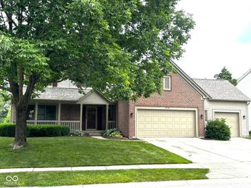 Charming brick home featuring a two-car garage, well-manicured lawn, and mature landscaping at 10760 Independence Way, Carmel, IN 46032