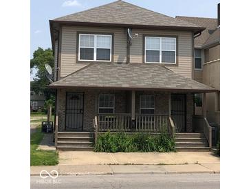 Two-story home with front porch featuring brick accents, gray siding and roofing, and traditional windows at 1421 S Meridian St, Indianapolis, IN 46225