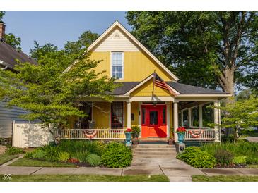 Charming yellow two-story home featuring a welcoming front porch, colorful red door and well-maintained landscaping at 224 N Pennsylvania St, Greenfield, IN 46140