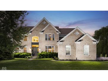 Elegant two-story brick home with manicured lawn and lush landscaping at twilight at 3876 Kegler Way, Carmel, IN 46074
