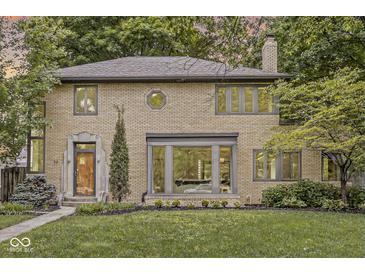 Charming brick home boasts mature trees, a landscaped yard, and unique architectural details at 518 Buckingham Dr, Indianapolis, IN 46208