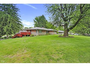 Expansive backyard with a lush lawn, mature trees, red patio and a well-maintained exterior at 7061 Maryann Ct, Indianapolis, IN 46227