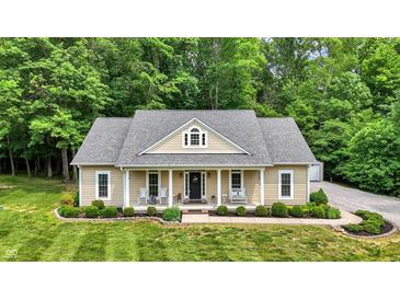 Charming home with a welcoming front porch, manicured lawn, and lush greenery at 7074 E Pine Needle Ln, Morgantown, IN 46160