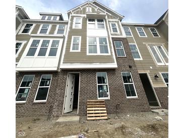 New construction of a brick and vinyl townhome exterior featuring white trim and many windows at 7313 Bayview Run, McCordsville, IN 46055