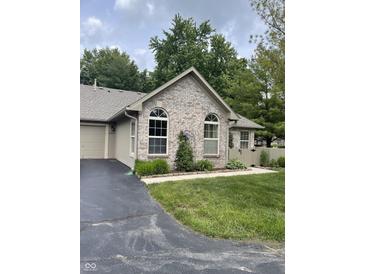 Charming home featuring a manicured lawn, arched windows, and a brick facade with beautiful landscaping at 7536 Briarstone Dr, Indianapolis, IN 46227
