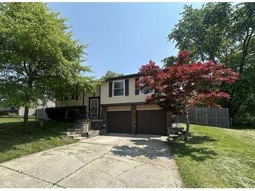 Charming split-level home featuring a two-car garage and mature trees in a well-manicured yard at 7607 Ardwell Ct, Indianapolis, IN 46237