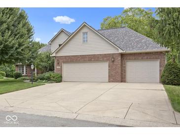 Charming home with a two-car garage, brick facade, and mature trees under a sunny sky at 9175 Lakewind Dr, Indianapolis, IN 46256
