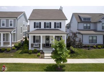 Charming two-story home with a welcoming front porch and manicured lawn and swing at 15557 Starflower Dr, Westfield, IN 46074