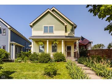 Charming two-story home featuring a covered front porch, lush landscaping, and an American flag at 2020 N Park Ave, Indianapolis, IN 46202