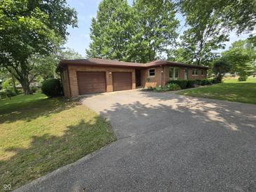 Charming brick home featuring a two-car garage and a long driveway lined with lush greenery and mature trees at 7088 Sandalwood Dr, Indianapolis, IN 46217