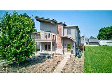 Modern home with a green door, a balcony, a manicured lawn, and attractive landscaping, showcasing contemporary design at 1622 Cornell Ave, Indianapolis, IN 46202