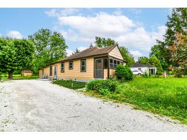 Cozy single-story home featuring a gravel driveway and lush green landscaping for a tranquil setting at 7829 Rahke Rd, Indianapolis, IN 46217