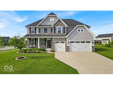 Charming two-story home featuring stone accents, gray siding, a manicured lawn, and a three-car garage at 4416 Eaglecrest Pl, Zionsville, IN 46077