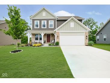 Inviting two-story home with landscaped lawn and a charming covered front porch and white two car garage at 5335 Rum Cherry Way, Indianapolis, IN 46237