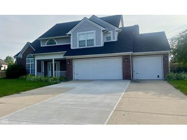 Charming two-story home with a brick facade, a two-car garage, a manicured lawn, and a freshly poured concrete driveway at 7532 Perilla Ct, Indianapolis, IN 46237