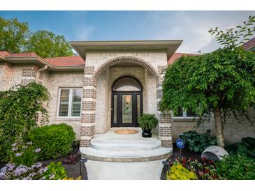 Elegant front entrance featuring arched doorway, brick accents, and landscaped garden at 8703 Gordonshire Dr, Indianapolis, IN 46278