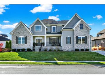 Beautiful two-story home featuring stone and siding, lush lawn, and professional landscaping at 13613 Lake Ridge Ln, McCordsville, IN 46055