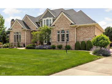 Stunning brick home with a lush green lawn and mature landscaping at 13888 Smokey Ridge Dr, Carmel, IN 46033