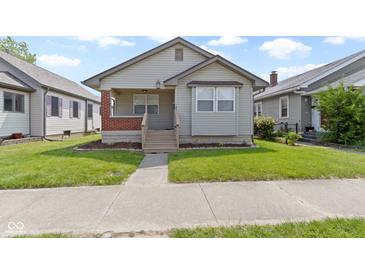 Charming single-story home featuring tidy front lawn, neutral siding, and welcoming front porch with brick detail and steps at 141 S 9Th Ave, Beech Grove, IN 46107