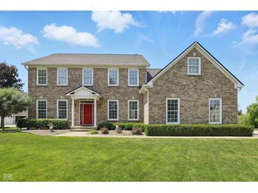 Brick two story home with a manicured lawn and a vibrant red front door exudes classic charm at 16802 Oak Manor Dr, Westfield, IN 46074