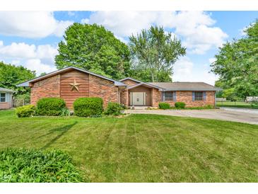 Charming single story brick home with a well-manicured lawn, mature trees, and an inviting facade at 407 Woodland E Dr, Greenfield, IN 46140
