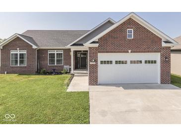 Charming brick home featuring an attached two car garage, manicured lawn and landscaped front yard at 5755 Victory Dr, Columbus, IN 47203