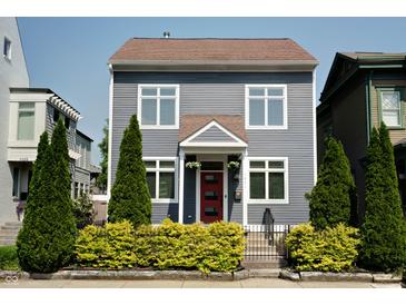Charming two-story home featuring gray siding, complemented by lush green landscaping and a vibrant red front door at 1021 N Alabama St, Indianapolis, IN 46202