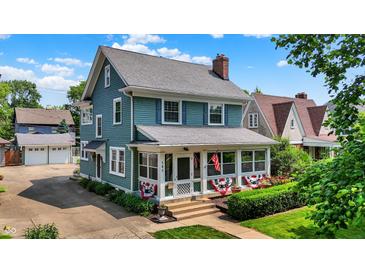 Charming two-story home with a welcoming front porch and well-maintained landscaping and a detached two car garage at 140 W Hampton Dr, Indianapolis, IN 46208