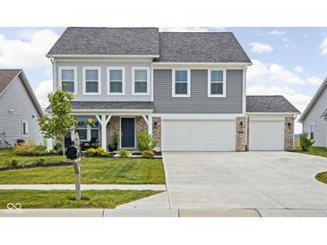 Two-story home featuring a three-car garage, well-manicured lawn, and a charming front porch at 6305 N Woodhaven Dr, McCordsville, IN 46055
