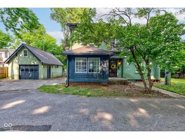 Charming home featuring green siding, blue accents, and a detached garage at 715 Kessler Blvd E Dr, Indianapolis, IN 46220