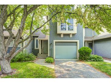 Charming townhome featuring a light blue garage door, shingled siding, and a walkway leading to the front door at 7507 Choate Ct, Indianapolis, IN 46254