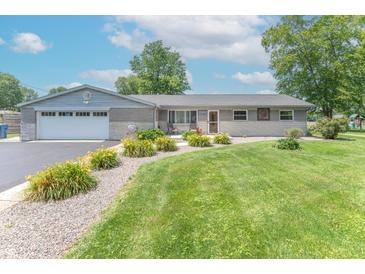 Charming single-story home with a well-manicured lawn, flower beds, and attached garage at 7850 S Mooresville Rd, Indianapolis, IN 46113