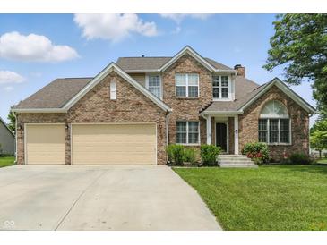 Charming brick two-story home with a three-car garage and well-manicured lawn and shrubbery at 10410 Trillium Ct, Noblesville, IN 46060