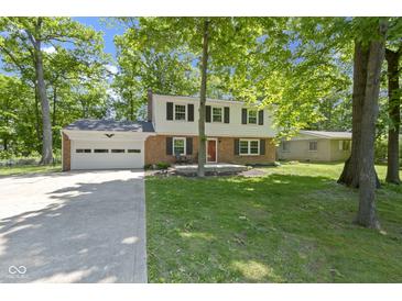 Charming two-story home featuring a brick facade, attached garage and a lush, tree-filled front yard at 11461 N College Ave, Carmel, IN 46032