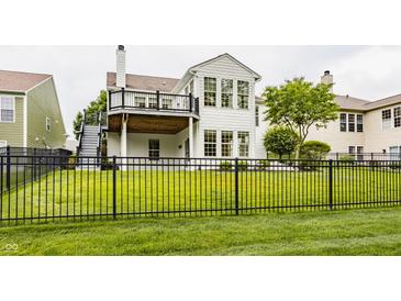 Beautiful backyard featuring an iron fence, lush green grass, a cozy deck, and mature trees at 13091 Duval Dr, Fishers, IN 46037