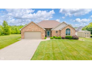 Charming brick home featuring an attached two-car garage, lush landscaping, and a well-maintained lawn at 1324 N Stewart Rd, Anderson, IN 46012