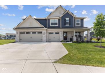 Charming two-story home featuring a three-car garage, a manicured lawn and a welcoming front porch with rocking chairs at , Westfield, IN 46074