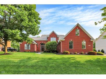 Beautiful red brick home with a well-manicured lawn and mature trees under a blue sky at 2614 Daylily Ct, Westfield, IN 46074
