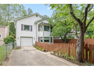 Charming two-story home with attached garage, bay window and lush landscaping at 5108 Riverview Dr, Indianapolis, IN 46208