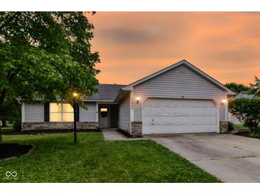 Charming single-story home with a well-maintained lawn and inviting two-car garage at sunset at 5651 Pine Knoll Blvd, Noblesville, IN 46062