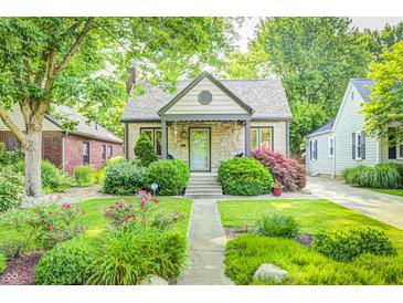 Charming home featuring a stone facade, manicured lawn, mature trees and beautiful landscaping at 6045 Haverford Ave, Indianapolis, IN 46220