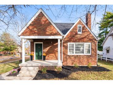 Charming brick home featuring a cozy front porch, green door, and manicured landscaping at 6640 E Washington St, Indianapolis, IN 46219