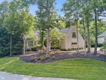 Charming brick home with a landscaped yard featuring mature trees and lush greenery at 9399 Irishmans Run Ln, Zionsville, IN 46077