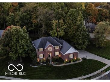 Aerial view of a brick two-story home with a well-manicured lawn and mature trees at 9703 Fortune Dr, Fishers, IN 46037