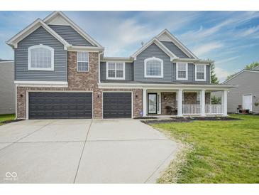 Charming two-story home featuring gray siding, brick accents, a welcoming front porch, and a two-car garage at 10903 Greenleaf Dr, Indianapolis, IN 46229