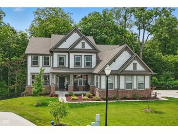 Beautiful two-story home featuring manicured lawn and charming architectural details and covered front porch at 16244 Perrault Ct, Fishers, IN 46040