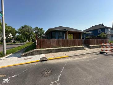 Charming single-story home with a fenced yard and bright yellow door, creating a welcoming curb appeal at 4402 E New York St, Indianapolis, IN 46201