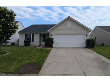 Charming single-story home featuring a two-car garage, manicured lawn, and inviting entryway at 581 Grassy Bend Dr, Greenwood, IN 46143